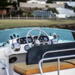 The steering wheel and control panel of a boat's cockpit, hinting at the mechanical components that answer the question, do houseboats have motors?